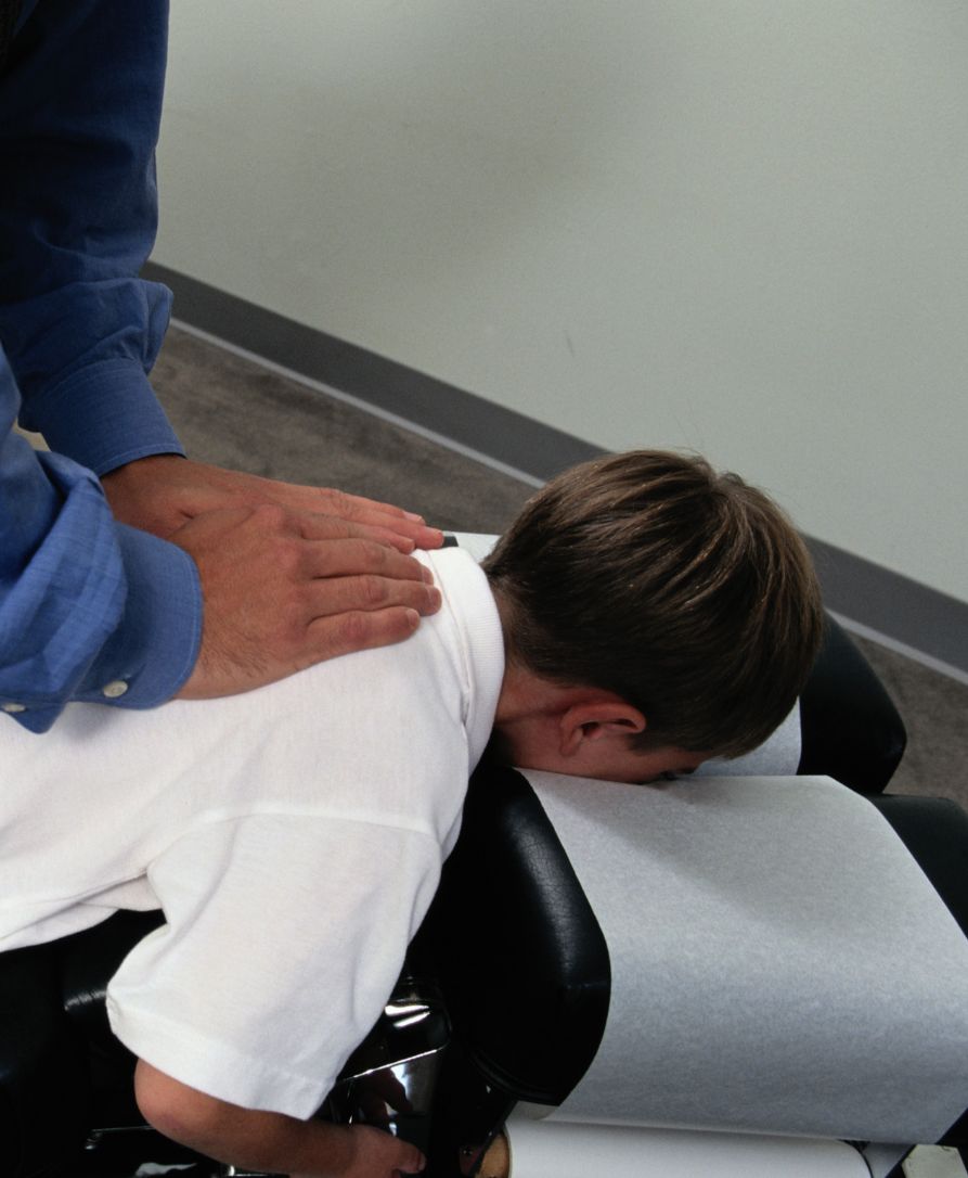 Chiropractor providing gentle pediatric adjustment to child's spine at Springdale clinic