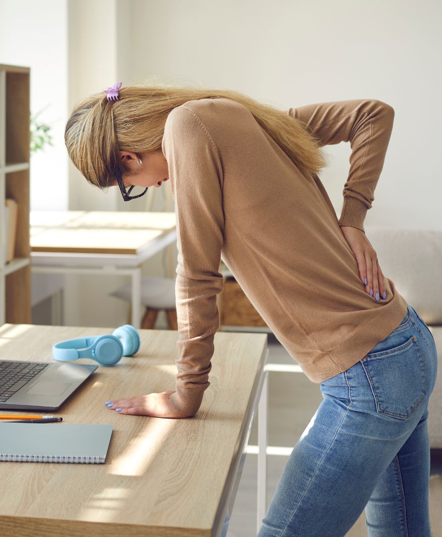 Person holding lower back experiencing sciatica pain and nerve discomfort seeking chiropractic relief